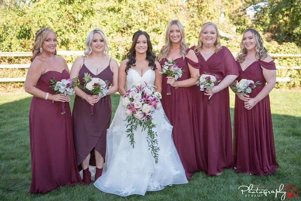 bride with her bridal party in burgundy dresses with burgundy and  white bouquets