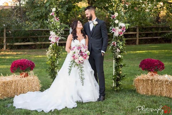 bride and groom under a wedding arch covered with burgundy and white flowers