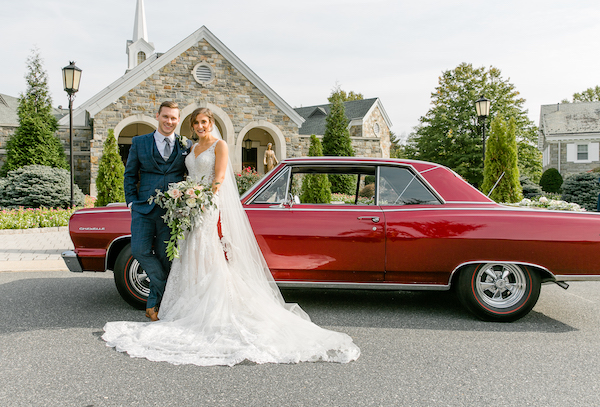 bride and groom posing for photos in front of a classic red Chevelle