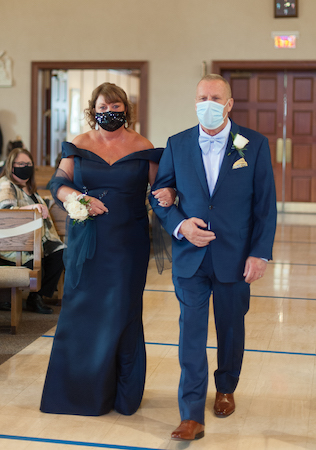 Parents walking down the aisle with boutonniere and wrist corsage