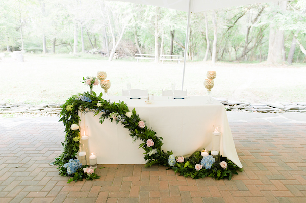 sweetheart table with floral garland and floating candles