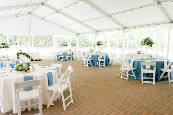 physically distant outdoor wedding under a tent with blue and white linens