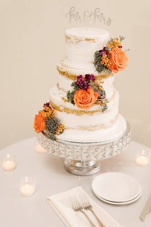 naked wedding cake with purple and orange flower