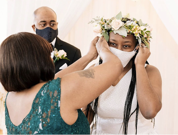 Mother of the bride assisting the bride with her custom mask designed to match her wedding gown