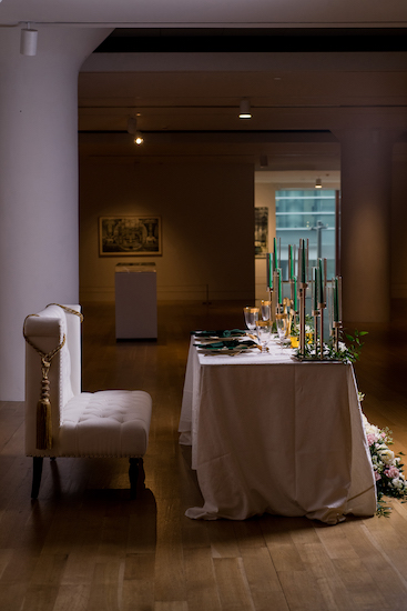 side view of an elegant sweetheart table with modern love seat and hunter green and gold decor